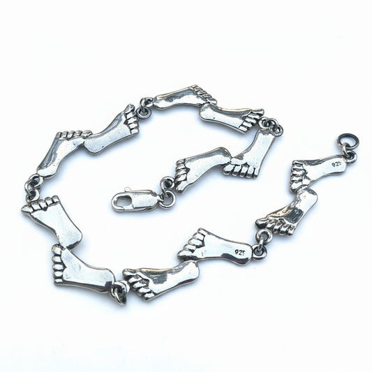 Silver foot-shaped bracelet on a light gray background